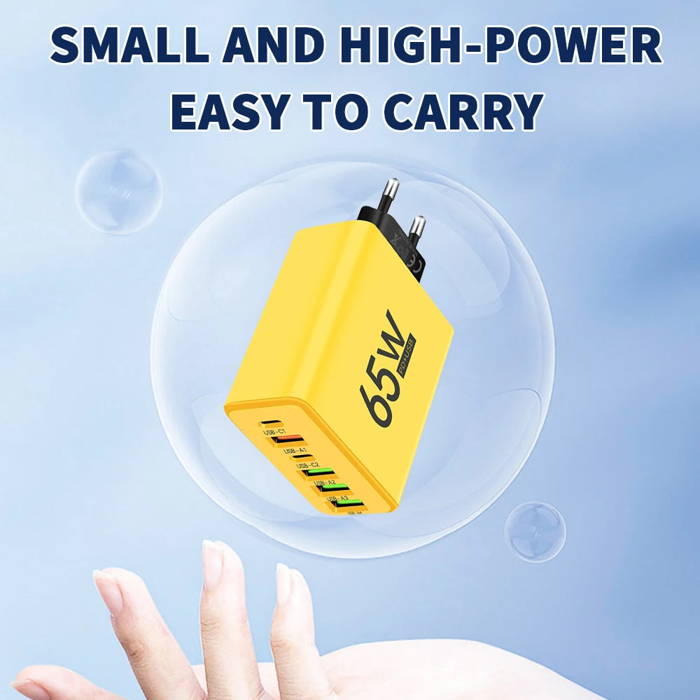 Yellow power adapter with '65W' rating held by a hand against a blue background
