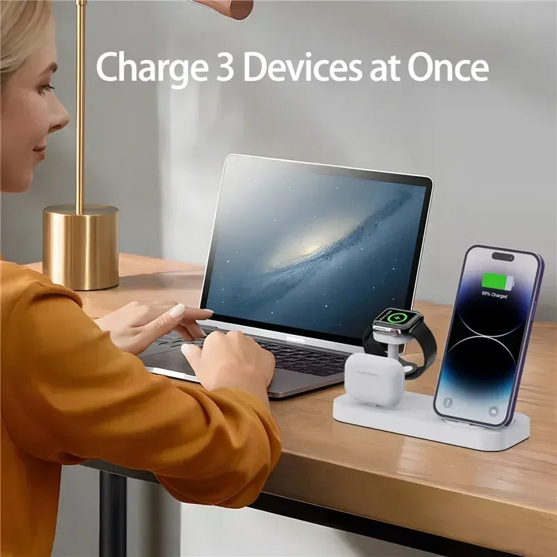 Person using a desk setup with a laptop, phone, and smartwatch on a charging station.