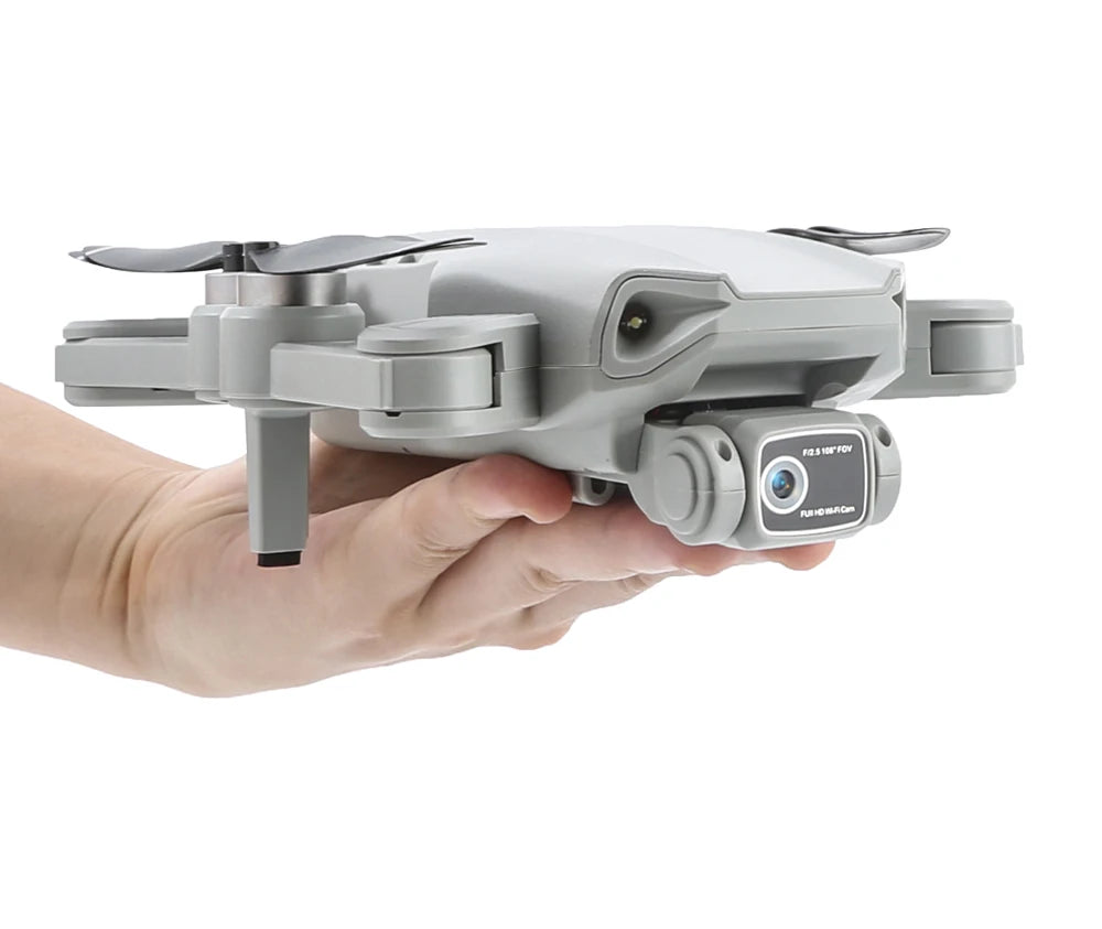 Gray drone held in a hand against a white background