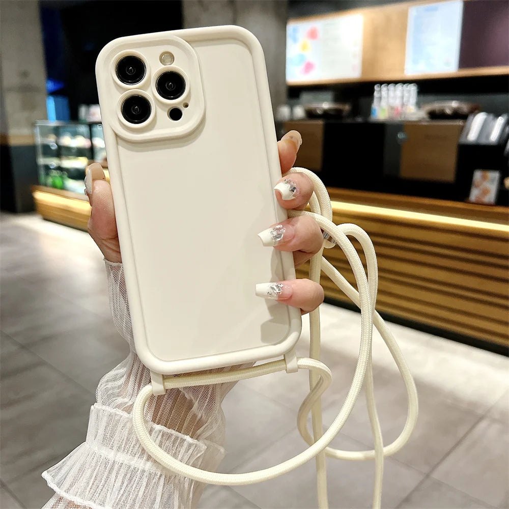 Person holding a phone with a beige case and strap in a blurred indoor setting