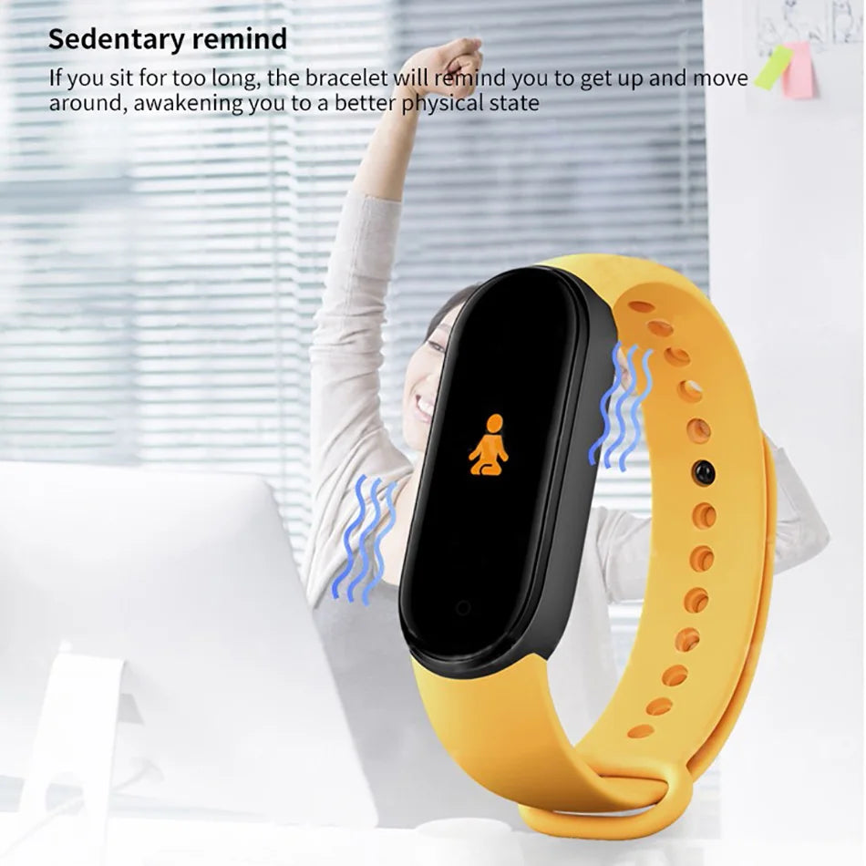 Yellow fitness tracker with black screen worn by a person, against a blurred indoor background.