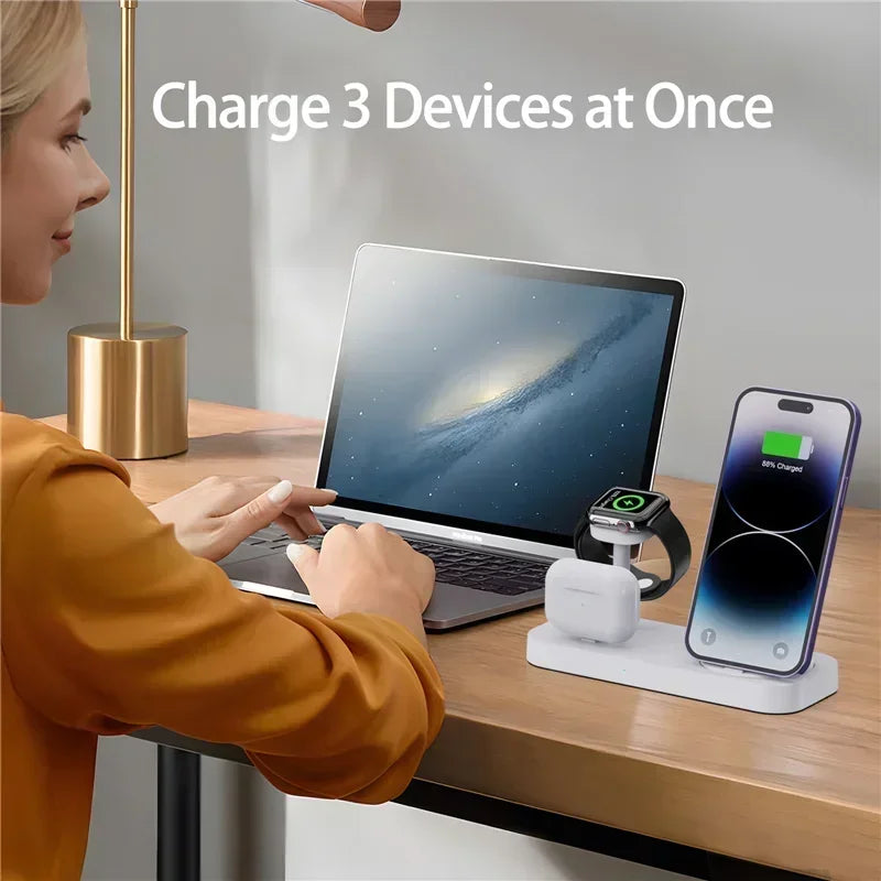 Person using a desk setup with a laptop, smartphone, and smartwatch on a charging station.