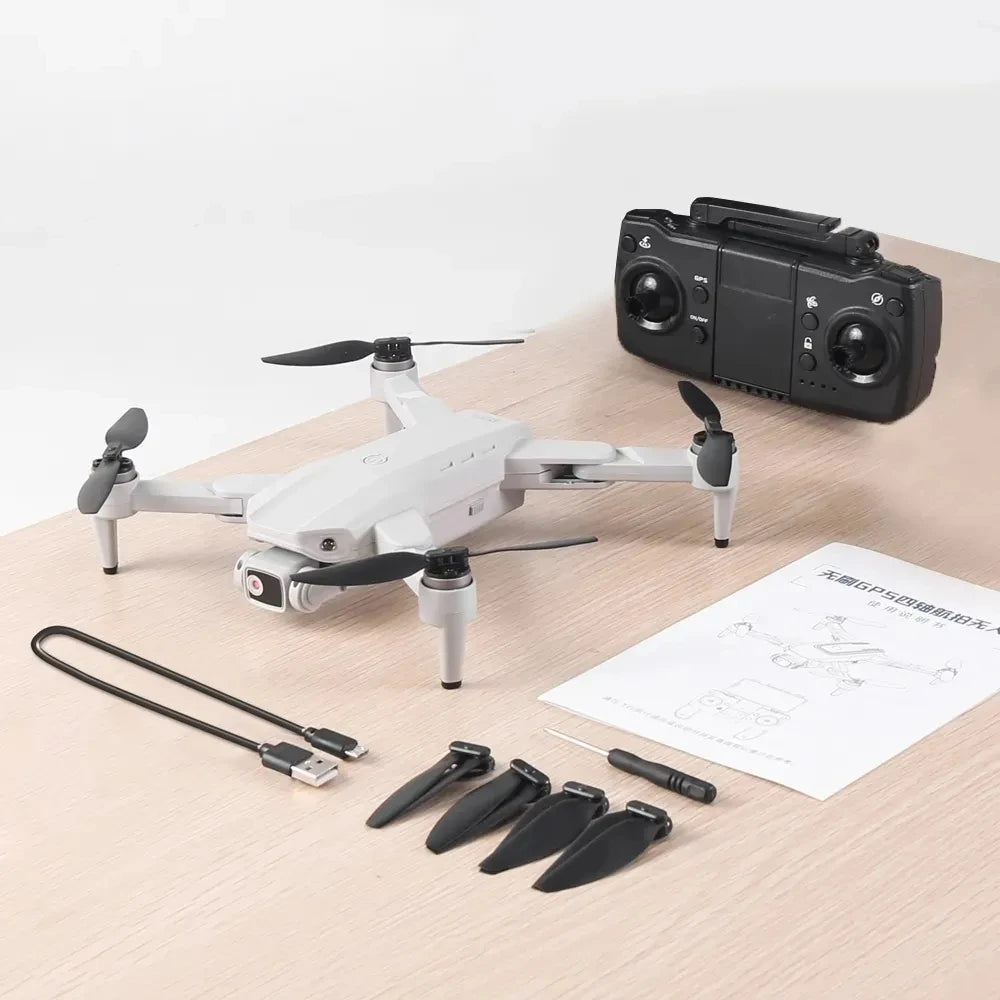 White drone with propellers, remote control, and cables on a wooden surface.