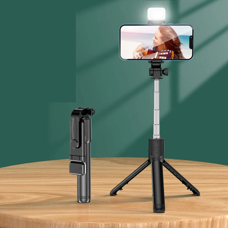 Smartphone with a selfie stick and light on a wooden surface against a green wall
