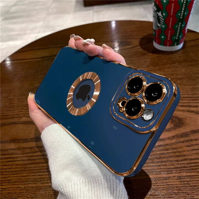 Blue phone case with gold accents held by a hand on a wooden table.