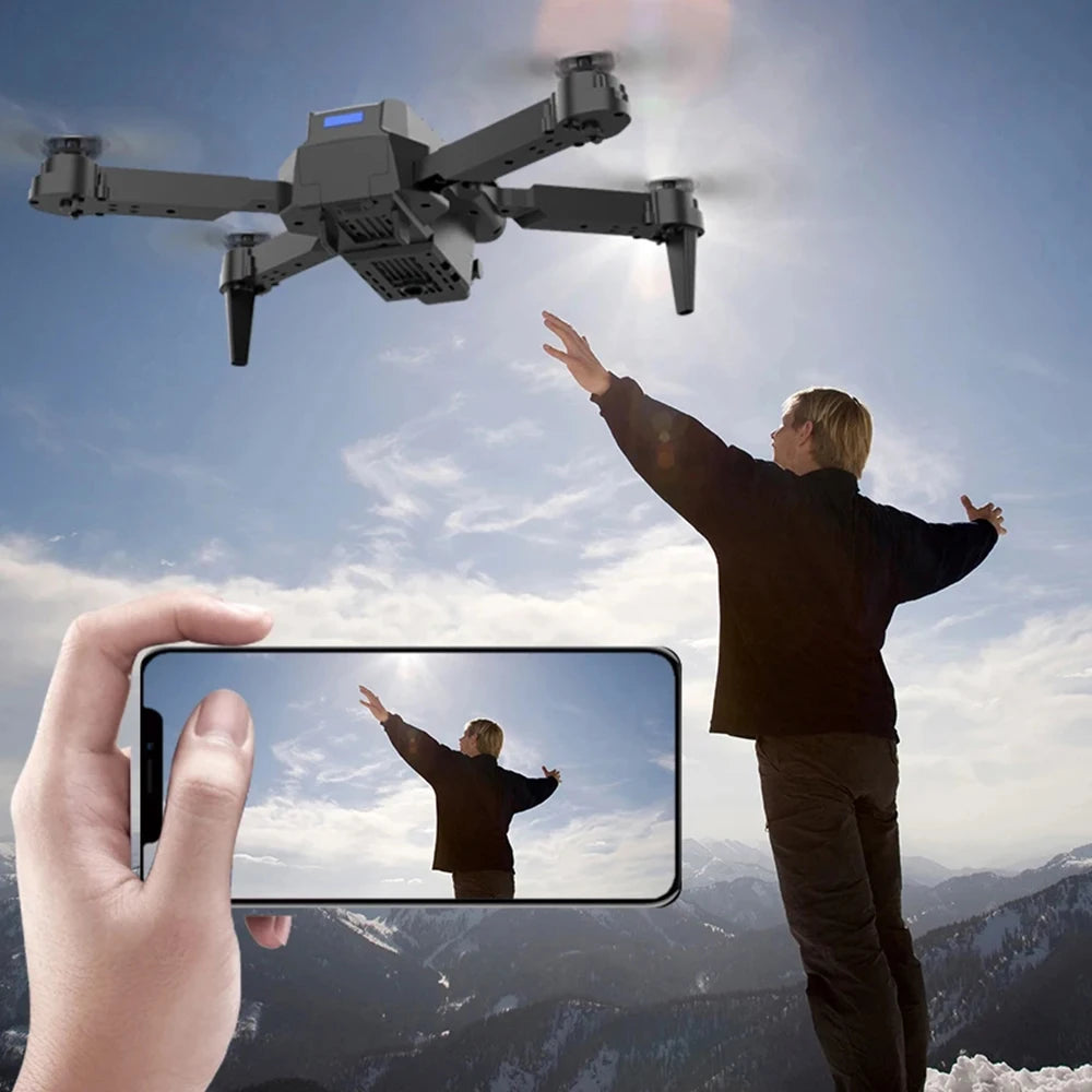 Person controlling a drone with a phone, set against a mountainous landscape.