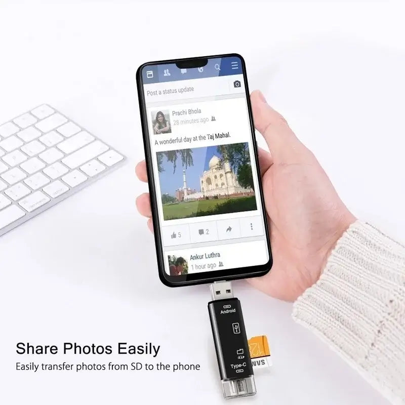 Hand holding a smartphone with a social media app open, connected to an SD card reader on a white surface