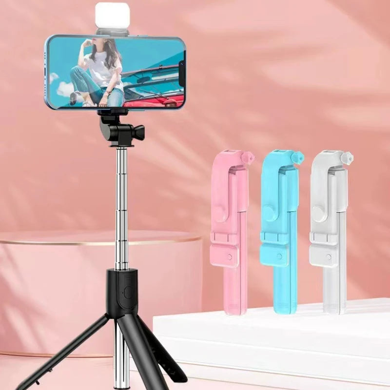 Phone holder with tripod and remote control on a pink background