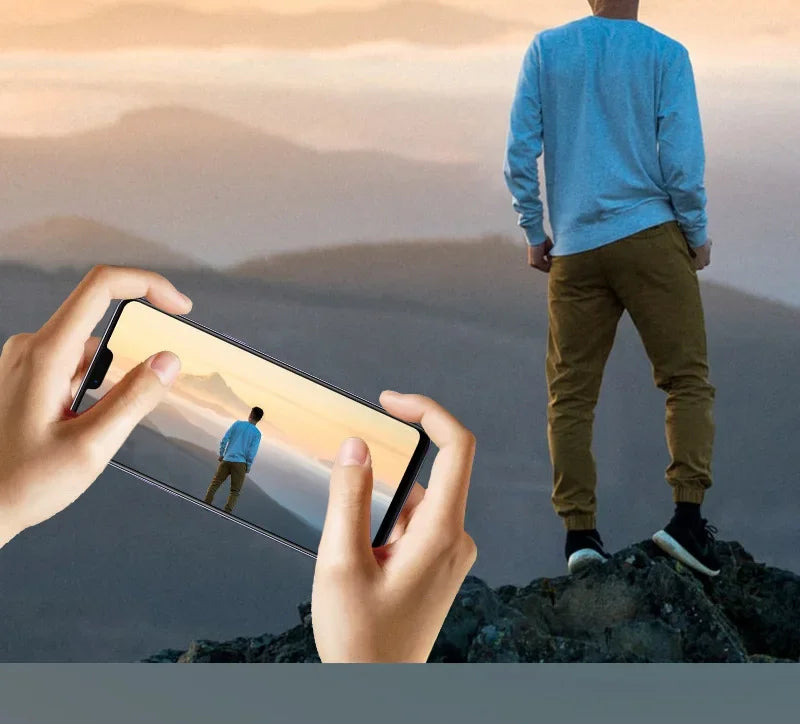 Person taking a photo of another person standing on a rock with a phone.