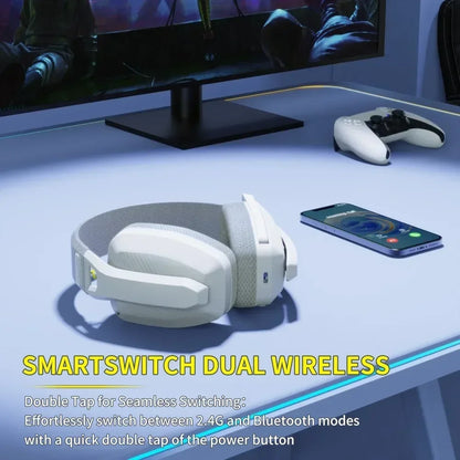 White gaming headset on a desk with a monitor, controller, and phone in the background.