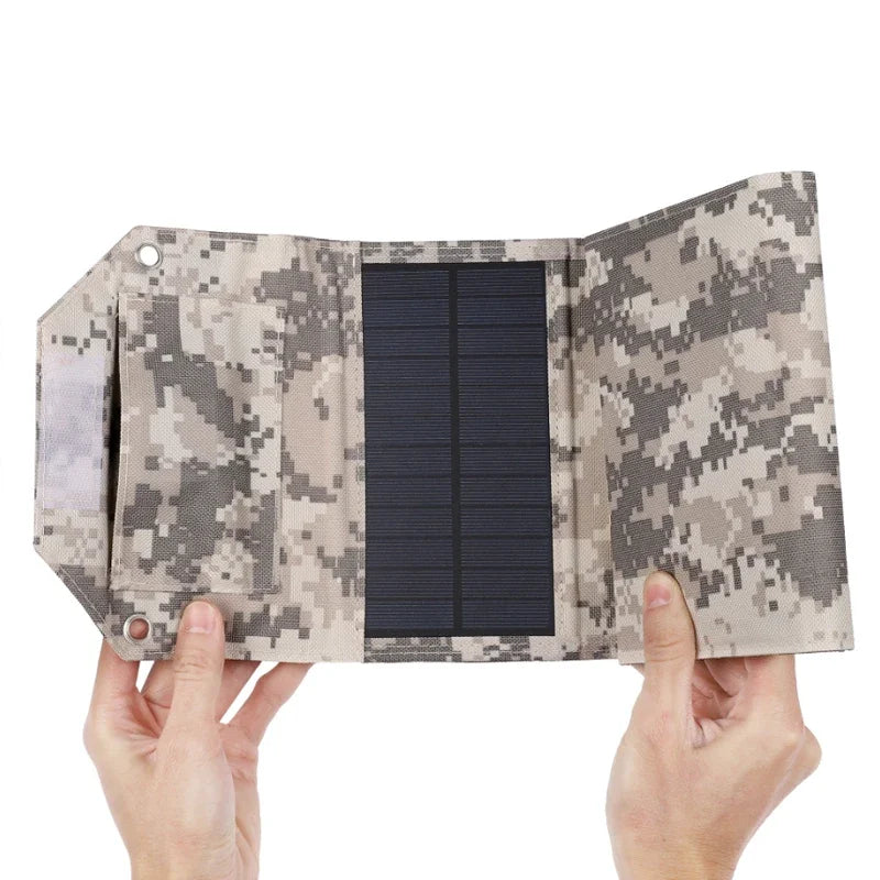 Camouflage-patterned solar panel held by hands on a white background