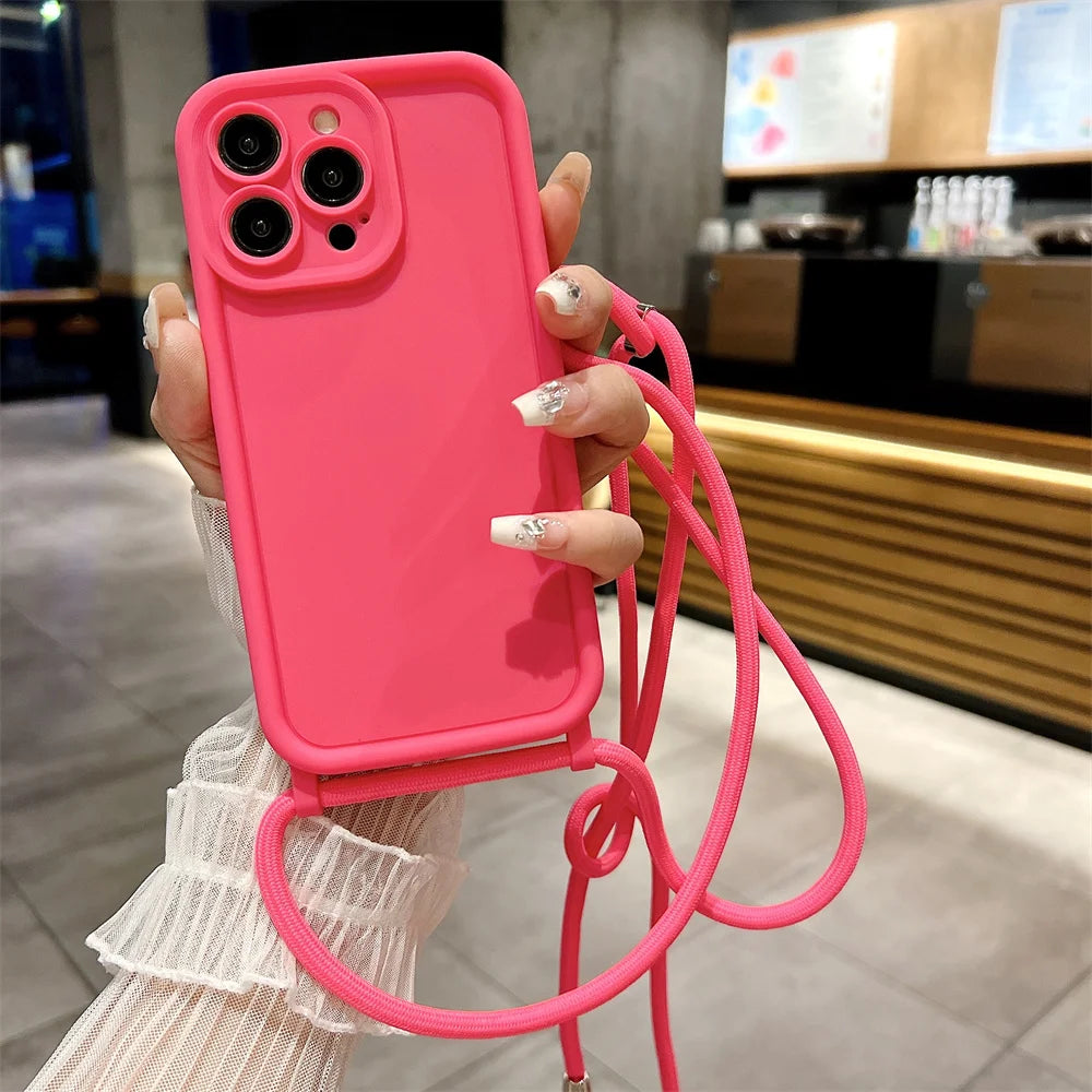 Person holding a pink phone case with a strap in an indoor setting