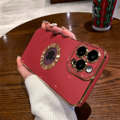 Red phone case with gold accents held by a hand on a wooden table.