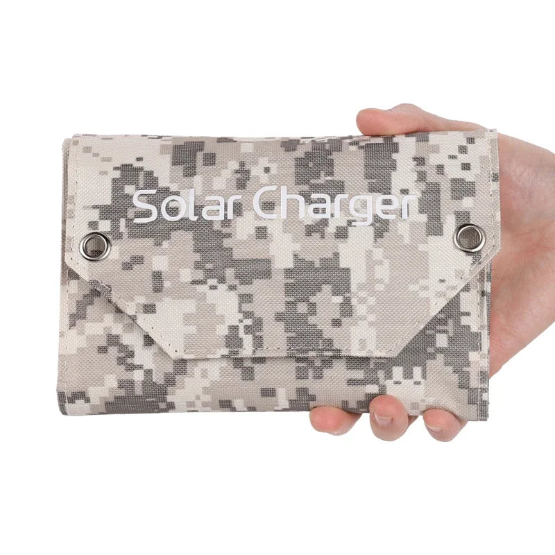 Camouflage solar charger held in a hand against a white background