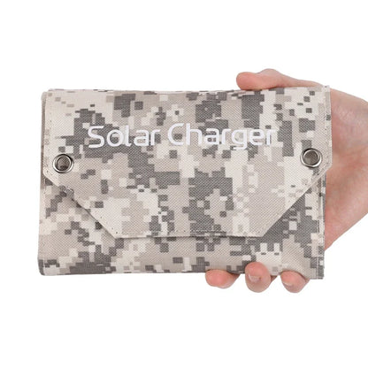 Camouflage solar charger held in a hand against a white background