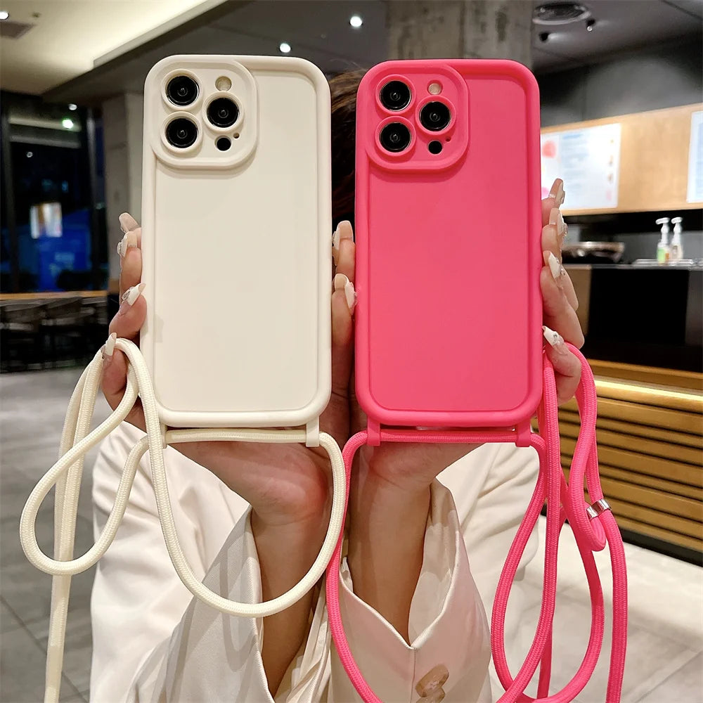 Two phone cases, one white and one pink, held by a person with straps.