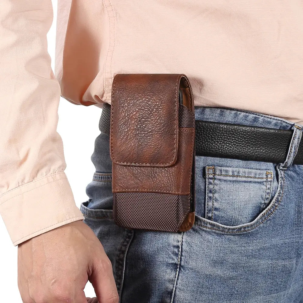 Person wearing a brown leather phone holster on a belt
