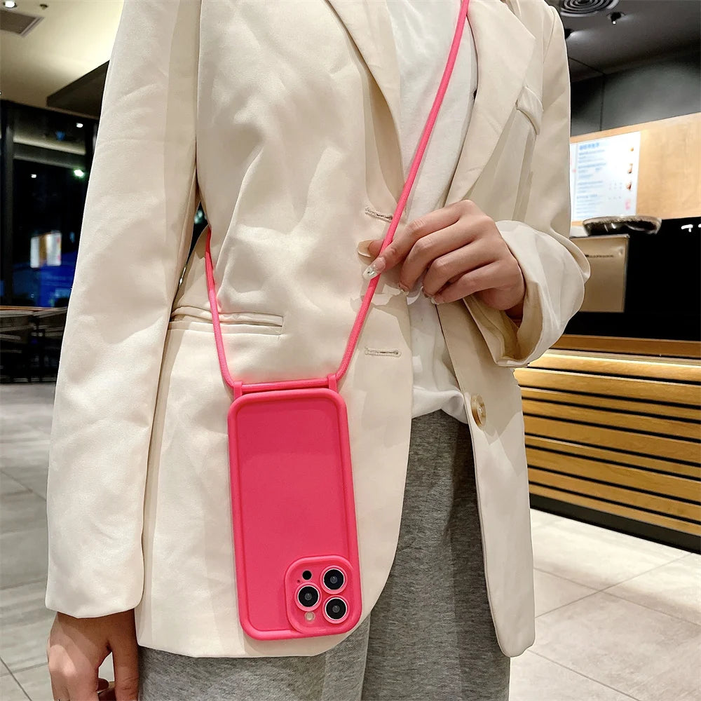 Person wearing a pink phone case with a strap, standing indoors.