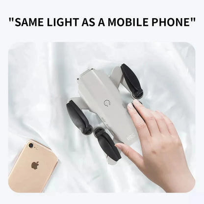 Hand holding a white electronic device with black accents next to an iPhone on a light background