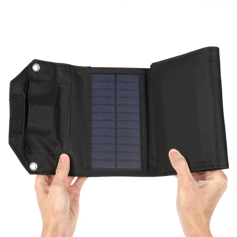 Black solar panel with a textured surface held by two hands against a white background