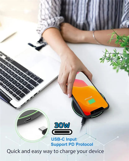 30W wireless charging pad with USB-C input charging smartphone on desk beside laptop.