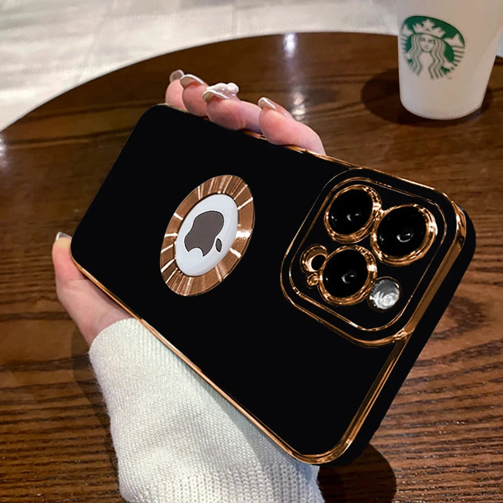 Black phone case with gold accents held by a hand on a wooden table with a Starbucks cup in the background.